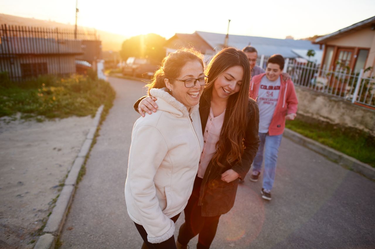 Eine junge Familie geht einen Bürgersteig entlang und genießt das Beisammensein