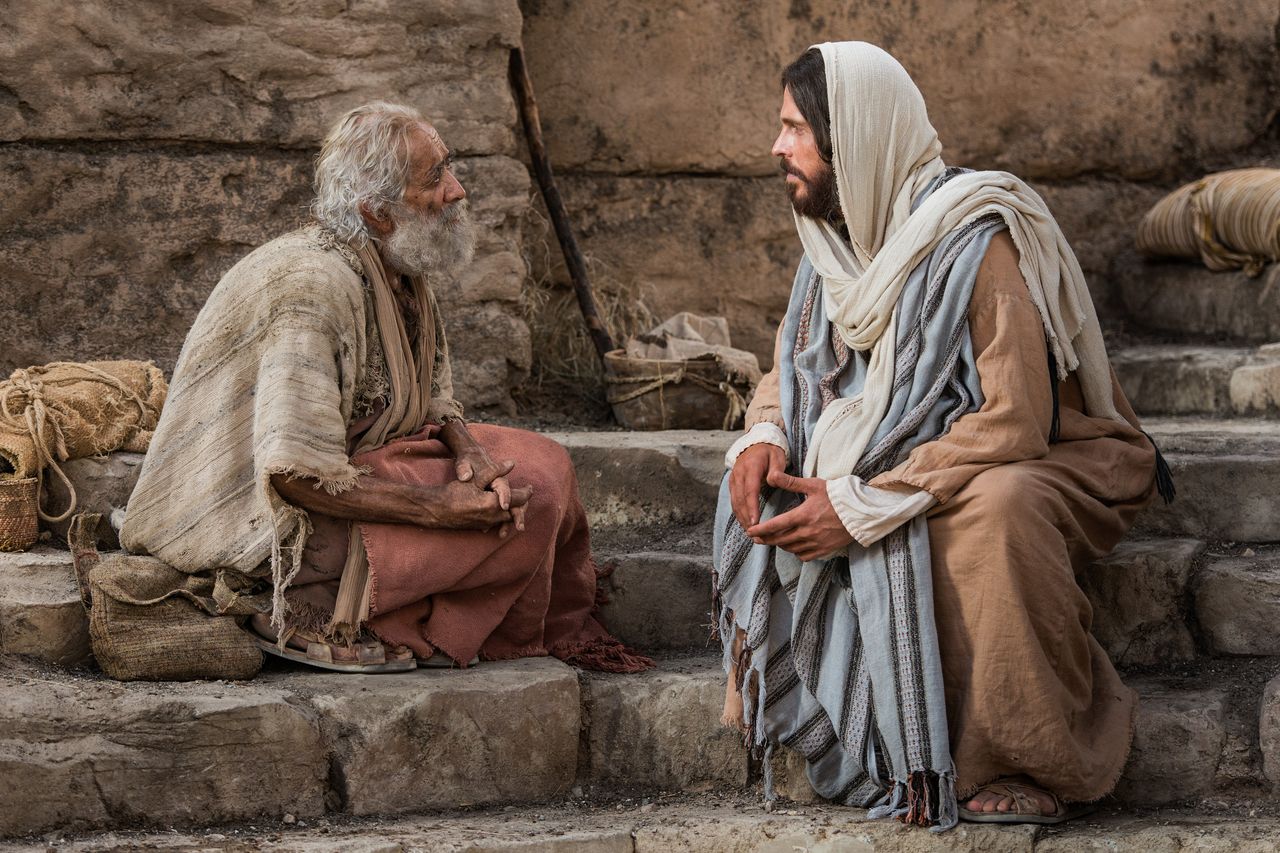 Jesus Christus sitzt mit bei einem Mann, den er geheilt hat, am Teich von Betesda